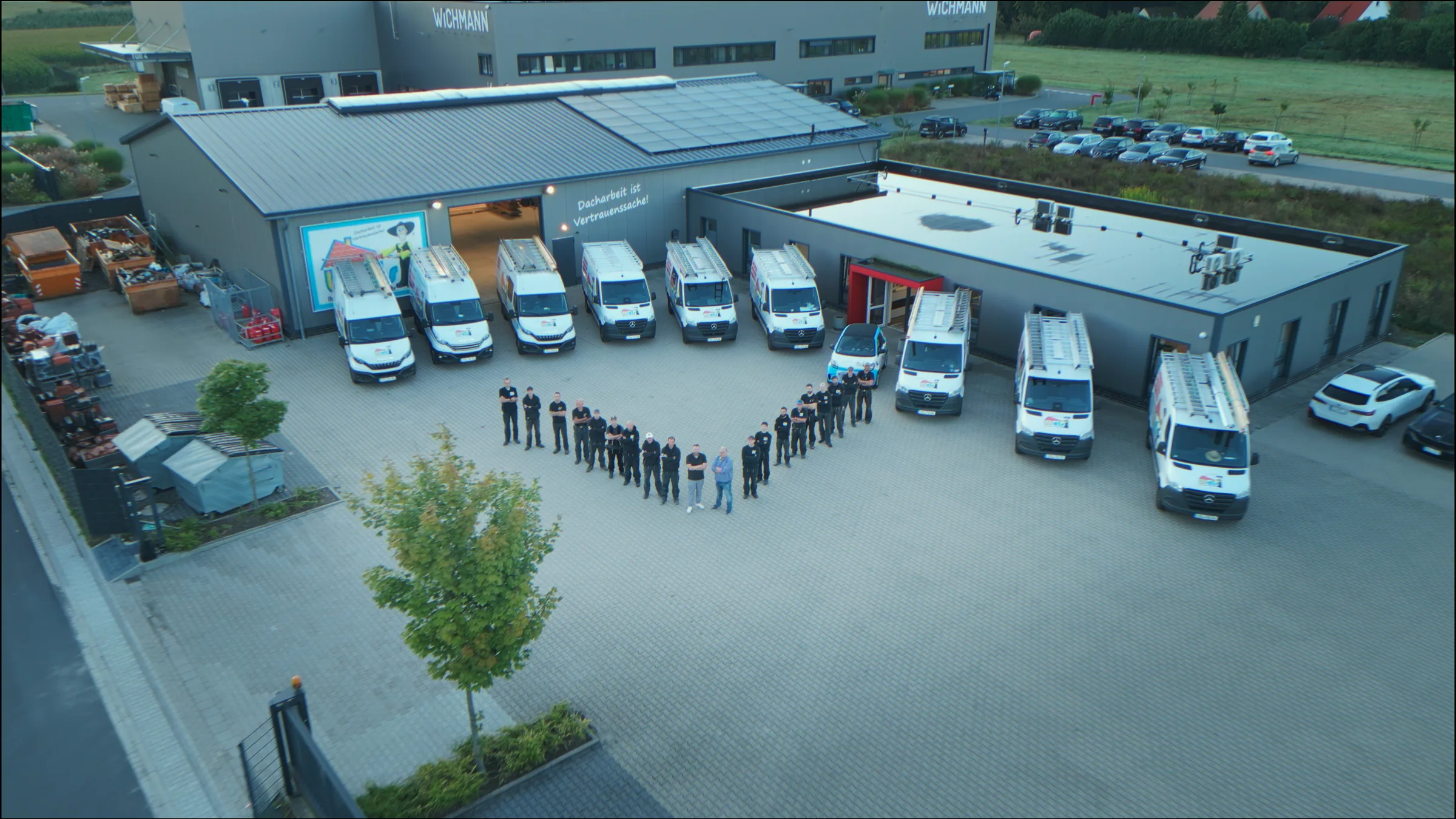 Luftaufnahme: Wels-Team steht vor Firmengebäude und Transportern in Lotte
